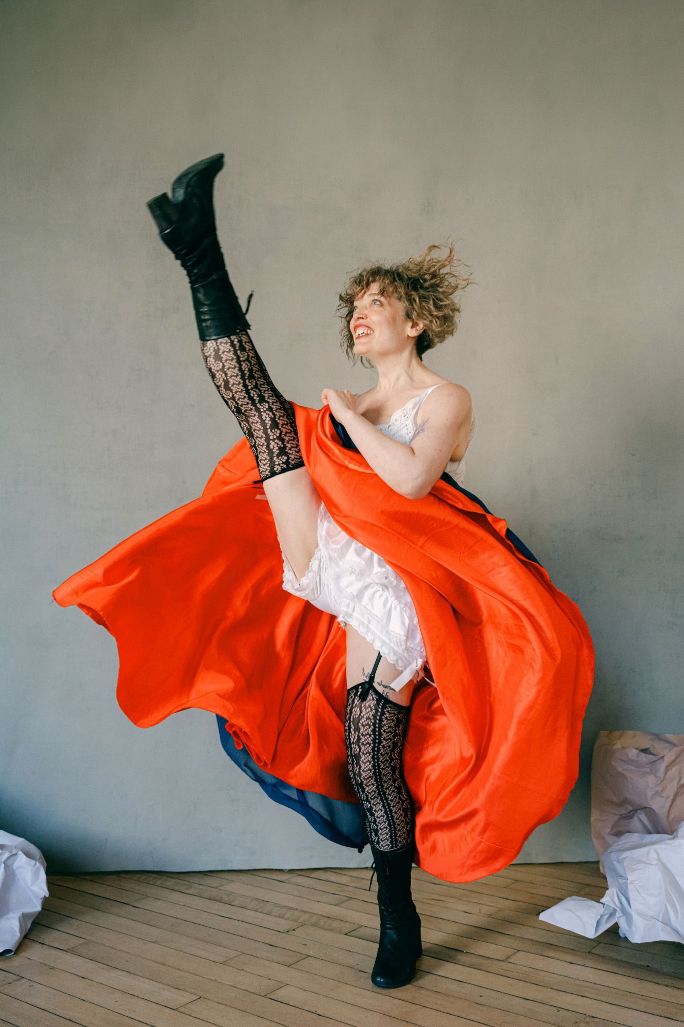 Saint Stella, Toronto multidisciplinary performer, mid high kick in a swirling red cancan skirt, white bloomers and lace stockings. Photo by Sylwia Kowalczyk