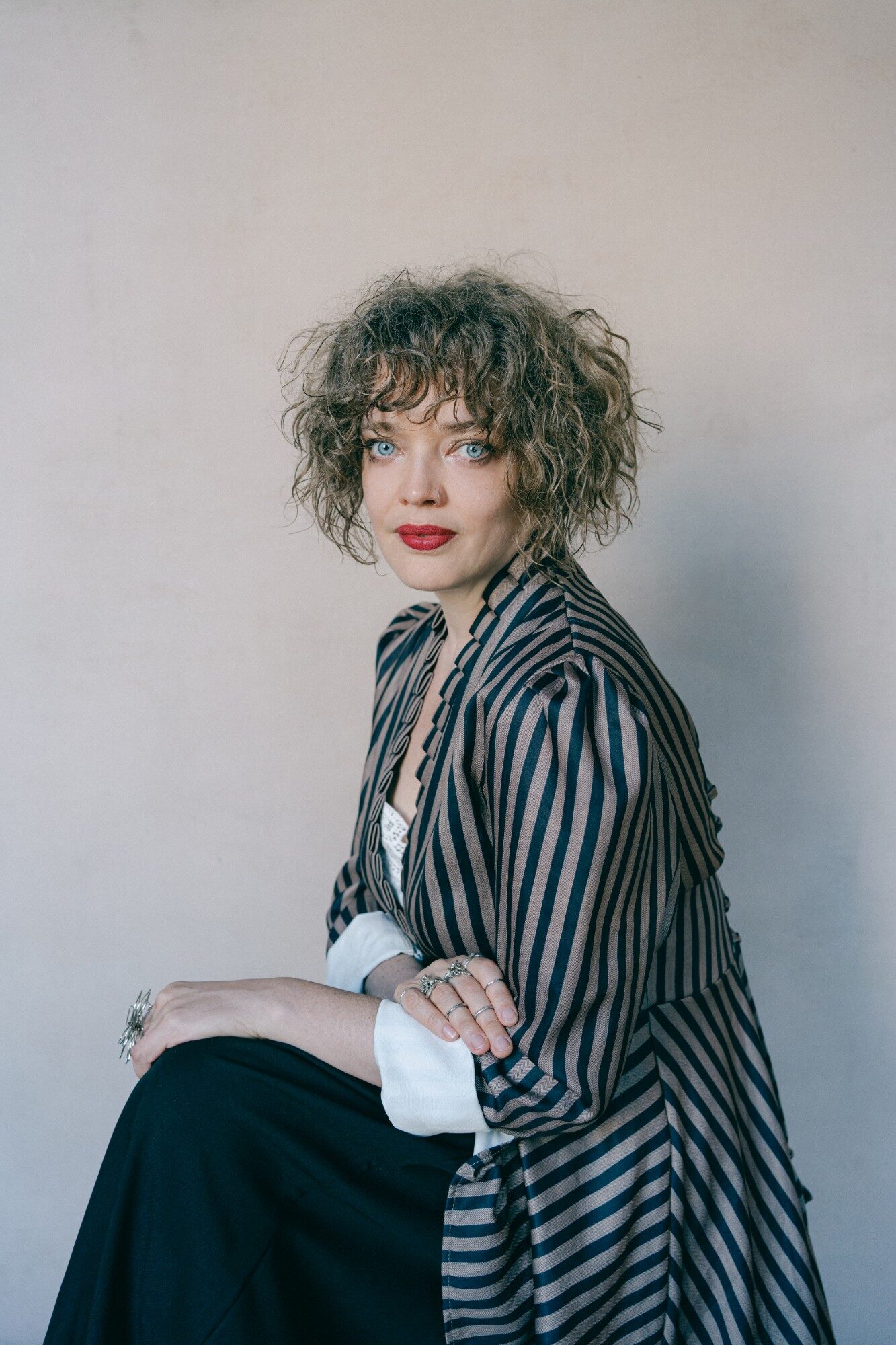 Portrait of Saint Stella, Toronto multidisciplinary performance artist, in a striped period coat and red lipstick. Photo by Sylwia Kowalczyk